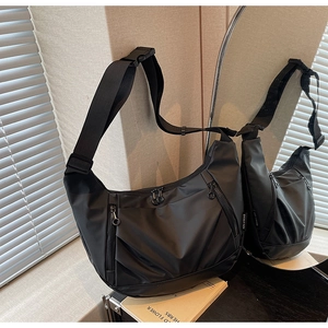 Detail view of black oxford crossbody bag with multi-compartment design and ring zippers