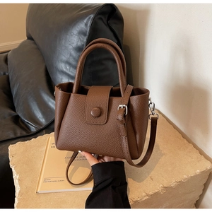 Gros plan du sac seau marron avec texture litchi sur surface en pierre avec anse