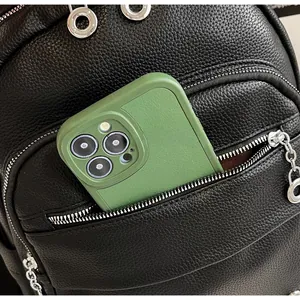 Detail of black pebbled leather backpack showing a phone fitting into the front zipper pocket