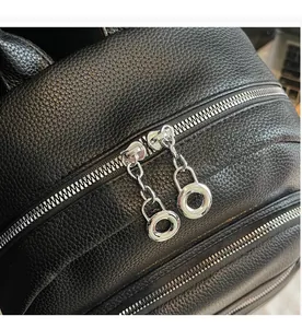 Detailed macro view of smooth silver metal zippers on black lychee grain leather backpack