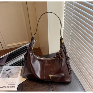 Gros plan du sac hobo en cuir huilé marron foncé avec fermeture éclair et nœud tressé