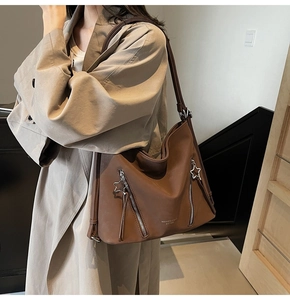 Detail of a brown leather shoulder bag with star-shaped zippers and brand lettering