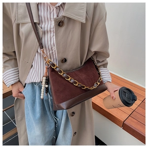 Detail of dark brown suede crossbody bag with gold chain and beaded tassel charm