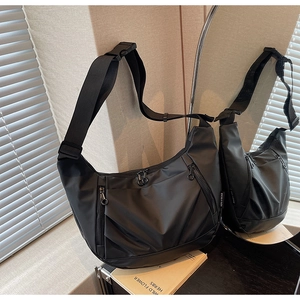 Close-up of black nylon crossbody bag featuring adjustable strap and buckle on side