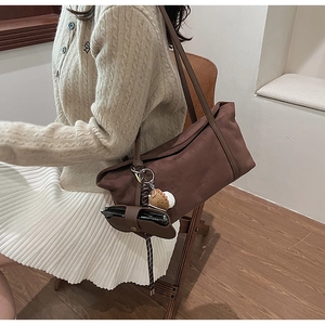 Détail du sac cabas en daim marron foncé avec charme en peluche et petite pochette assortie