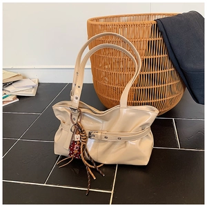 Gros plan d'un sac porté épaule en cuir verni beige avec boucle et charm imprimé léopard