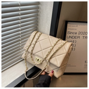Detail of warm beige quilted shoulder bag with gold clasp and leather chain strap