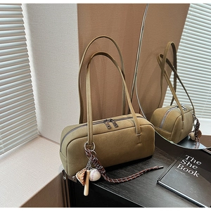 Detail einer olivgrünen Boston-Tasche mit Doppelriemen und Baseball-Anhänger-Zubehör
