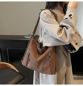 Detailed close-up of brown tote bag with decorative star zippers and brand logo