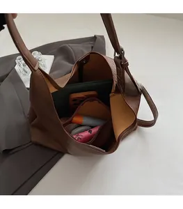 Detailed interior of large brown leather bucket bag showing capacity with tablet and items