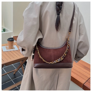Détail d'un sac seau marron en daim et cuir avec chaîne dorée et bandoulière chic