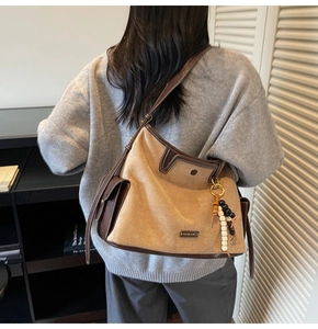 Detail of tan suede tote bag featuring contrast stitching and wooden bead charm