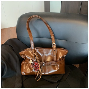 Détail d'un sac à bandoulière marron brillant avec pendentif ours léopard et boucles métal