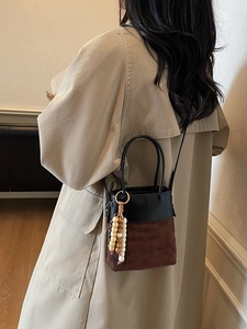 Vintage suede bucket bag with leather patchwork and wooden bead charm on shoulder strap
