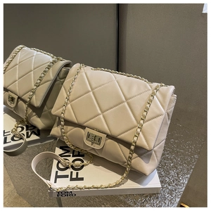 Detailed view of beige quilted faux leather handbag with gold chain strap and square lock