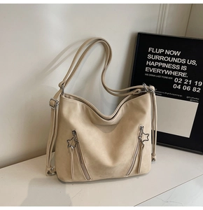 Detail of star-shaped silver zippers on a cream hobo tote bag with soft matte texture