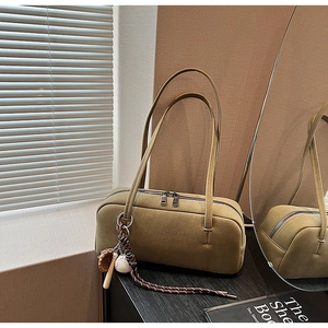 Detailansicht khakigrüne Baguette-Tasche mit Doppelriemen und Baseball-Anhänger