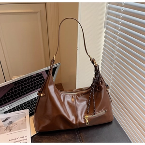 Détail d'un sac marron vintage avec poche zippée latérale et pendentif noeud en corde