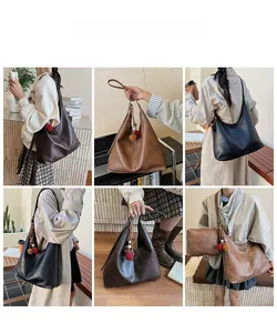 Detail view of large PU leather tote bag with plush ball charm in black and brown