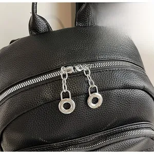 Detail of silver dual metal zippers and litchi texture on a black leather backpack