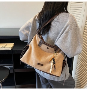 Close-up of khaki suede tote bag with brown leather trim and wooden bead tassel detail