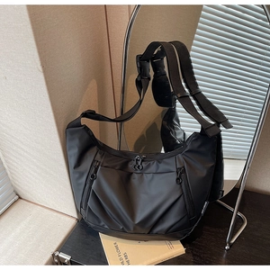Detail view of black oxford nylon crossbody bag with functional zippers and wide strap