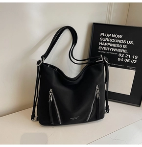 Detail of black matte leather tote bag with vertical metal zippers and white logo print