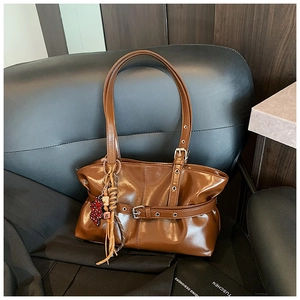 Détail du sac en cuir brillant caramel avec boucle décorative et breloque ours