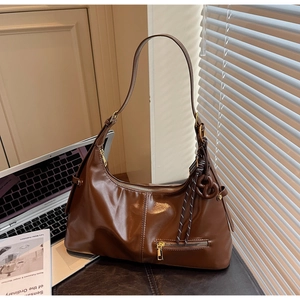 Gros plan d'un sac hobo vintage marron avec fermetures éclair dorées et breloque tissée