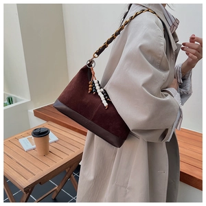 Détail du sac bandoulière en daim avec chaîne en métal et pendentif en perles décoratif