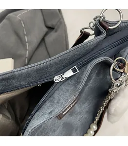 Detailansicht von silbernem Reißverschluss, Perlenkette und Denim-Stoffstruktur