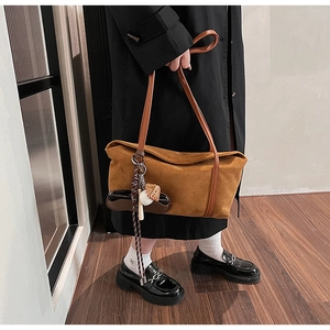 Détail du sac à bandoulière vintage en daim marron avec pompon et poignées en cuir