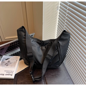 Close-up of black waterproof nylon crossbody bag with functional zippers in office setting