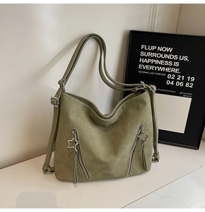 Detail of olive green suede tote bag with star zipper pull and elegant tassel accents