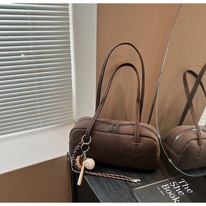 Detail der dunkelbraunen Wildleder-Boston-Bag mit Baseball-Anhängern und Doppelreißverschluss