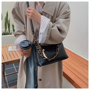Détail du sac à bandoulière tressé noir avec chaîne dorée et breloque en perles vintage