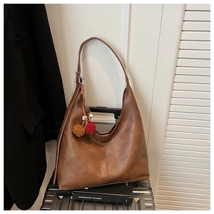 Close-up of brown PU leather tote bag with colorful pom-pom charms and detailed stitching