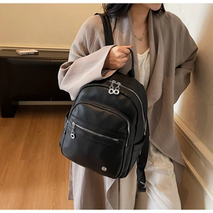 Side view of black pebble leather backpack with silver zippers on a model