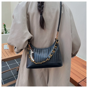 Détail du sac seau demi-lune tressé noir avec pompon en perles et bandoulière chaîne