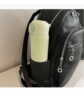 Detail of durable side pocket on black pebbled leather backpack holding a water bottle