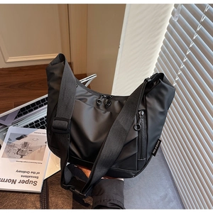 Detail of black nylon crossbody bag featuring adjustable wide strap and zip pockets