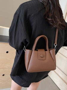 Brown litchi grain bucket bag with handles and silver buckles shown on a model