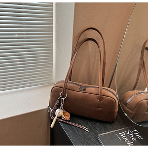 Detailansicht der braunen Wildledertasche mit Baseball-Anhänger und Doppelreißverschluss