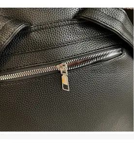 Close-up of smooth silver metal zipper on high-quality black litchi grain leather backpack