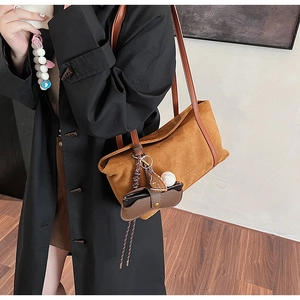 Détail du sac cabas en daim marron avec lanières en cuir et breloques décoratives