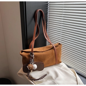 Détail du sac cabas en daim marron foncé avec breloques de baseball et lanières en cuir