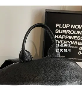 Detail showing reinforced stitching and lychee grain leather handle of black backpack