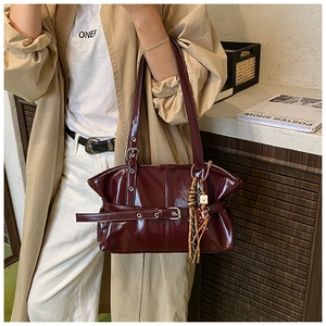 Détail d'un sac à main bordeaux brillant avec boucle rétro et charm d'ours
