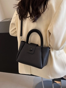 Elegant black lychee leather bucket handbag with round buckle and crossbody strap