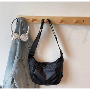 Detail of black oxford nylon crossbody bag with side logo tag and decorative zippers